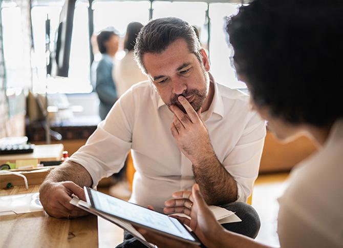 Two people looking at a tablet as they analyze their travel partner