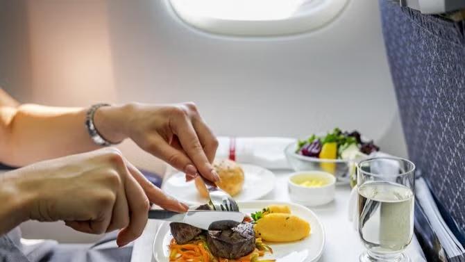 In-flight dinner service representing  the best ways to avoid jet lag and stay healthy for next long-haul flights.