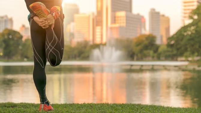 A person stretching facing a view of water representing  the best ways to avoid jet lag and stay healthy for next long-haul flights.