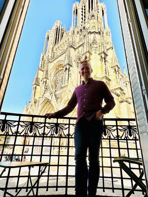 man smiling standing in front of a basilica 