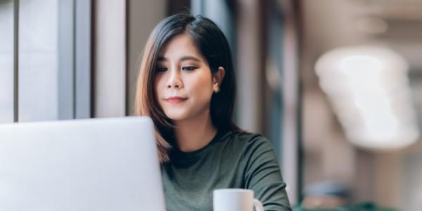 Portrait of Young Smart Asian Woman Freelance Online Working from Home with Laptop at Home Living Room in Coronavirus or Covid-19 Outbreak Situation